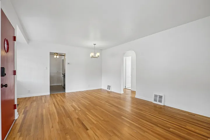 Spacious room with wood-finish flooring and a central chandelier