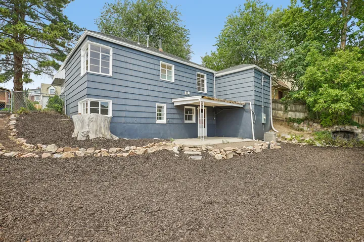 Rear exterior featuring blue siding, white-framed windows, and a covered concrete patio