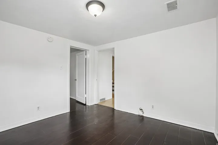 Interior room featuring dark wood-finish flooring, white walls, and a ceiling-mounted light fixture