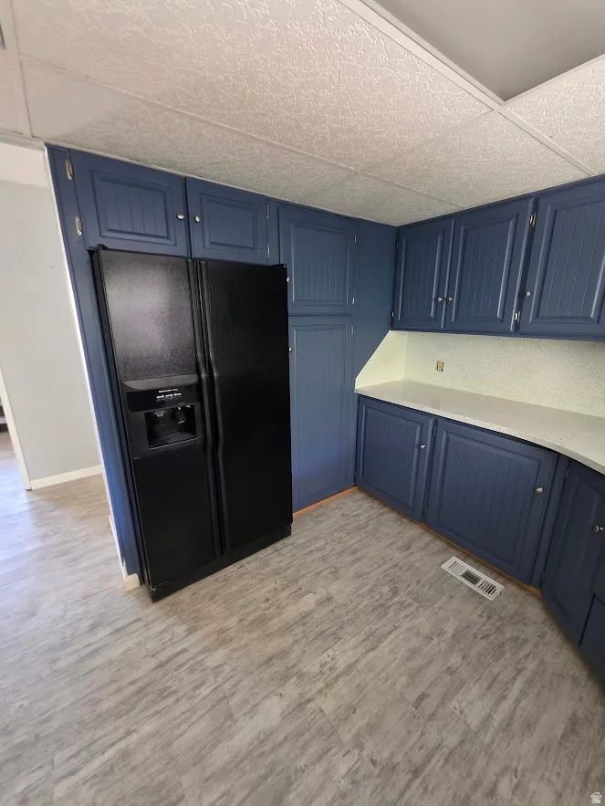 Kitchen featuring blue cabinetry, light countertops, and wood-finish flooring