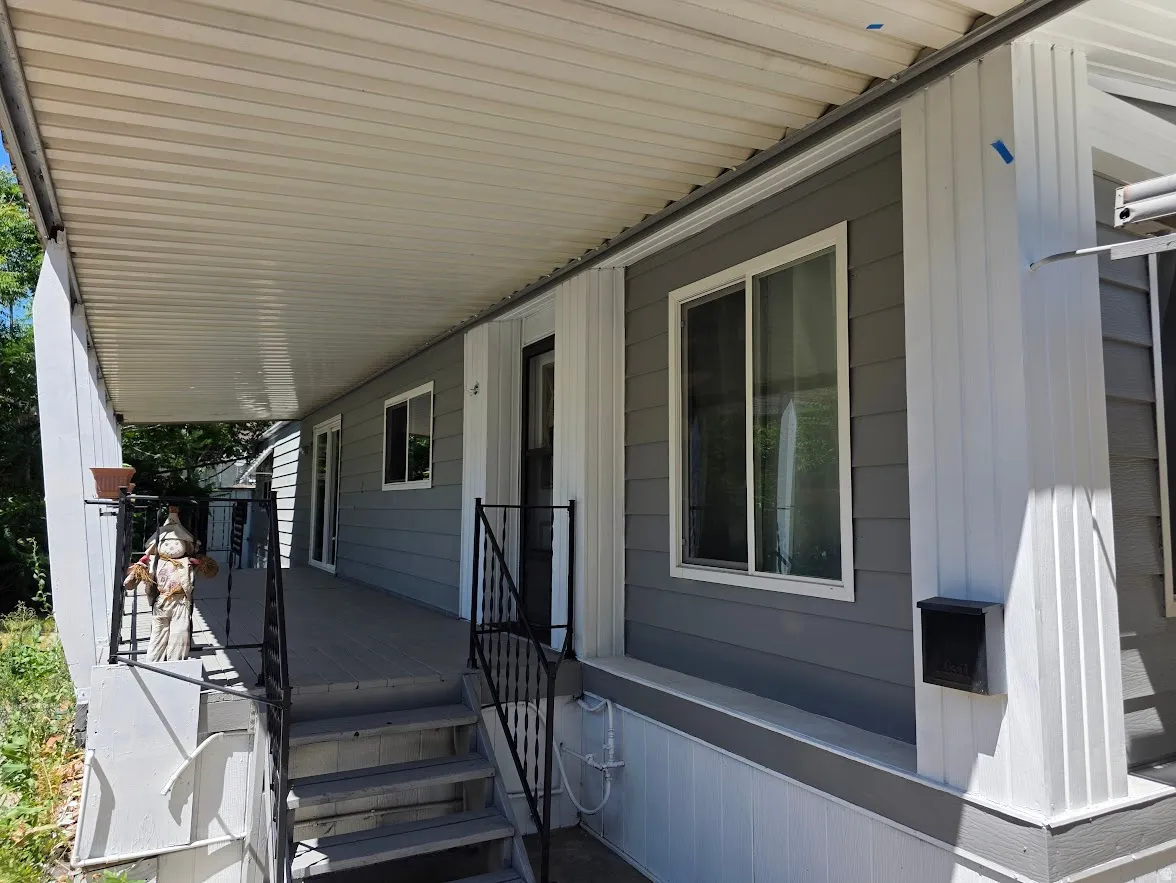 Covered exterior porch featuring grey siding, white trim, and dark-finished metal railings