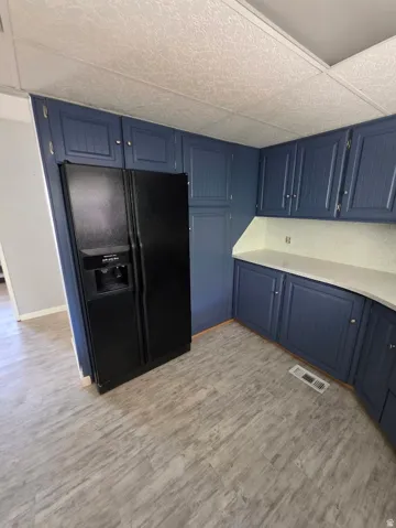 Kitchen featuring blue cabinetry, light countertops, and wood-finish flooring
