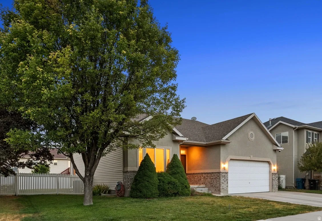 Contemporary stucco exterior with a stone veneer accent, attached two-car garage, and a manicured front lawn