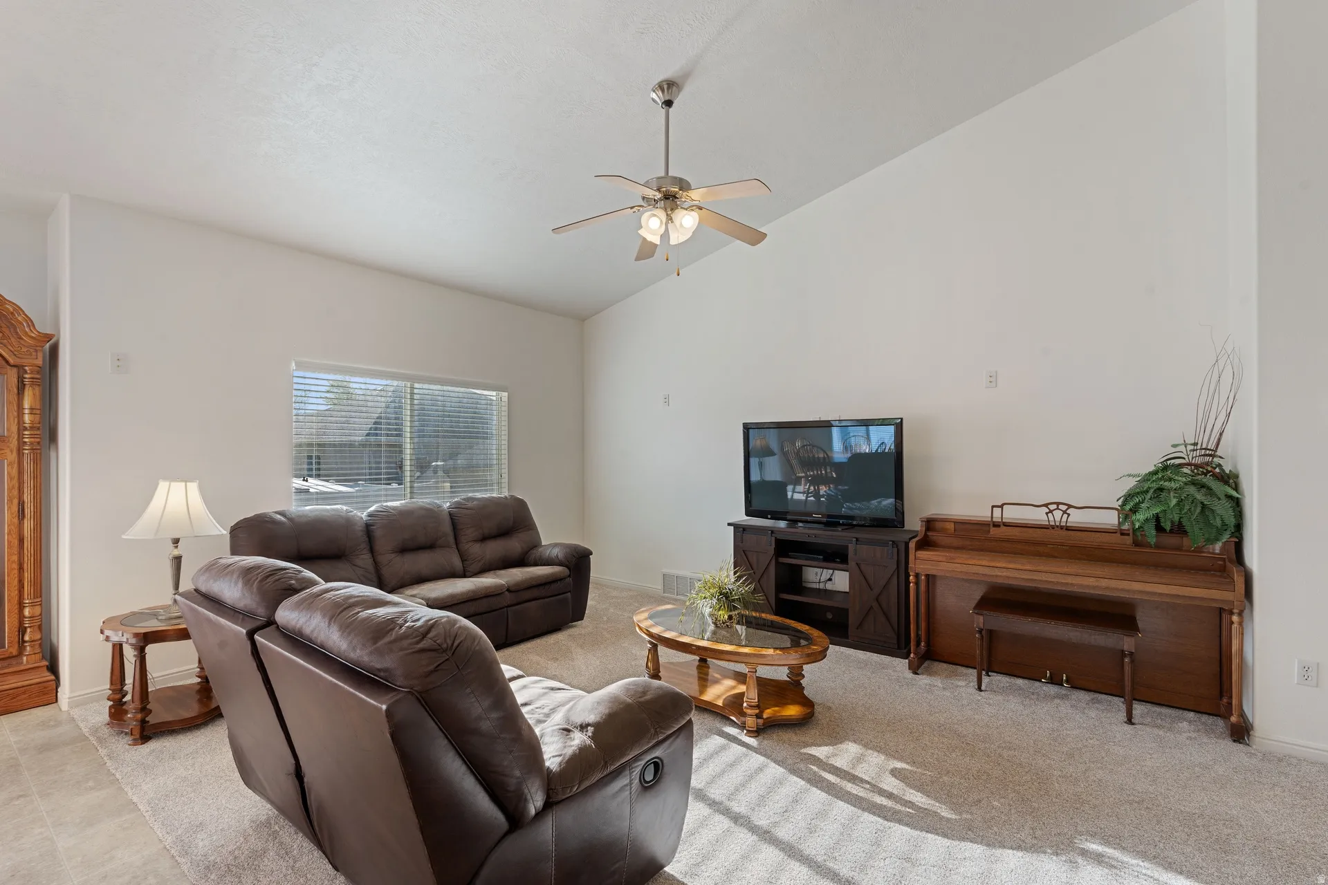 Spacious living area featuring vaulted ceilings, recessed window, and light-toned carpet flooring