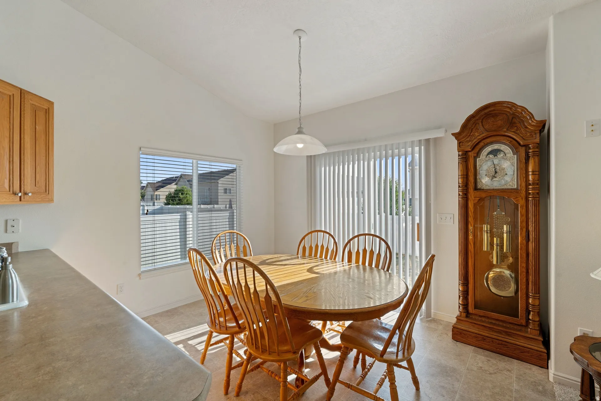 Dining area featuring a vaulted ceiling, durable tile flooring, and a window with horizontal blinds