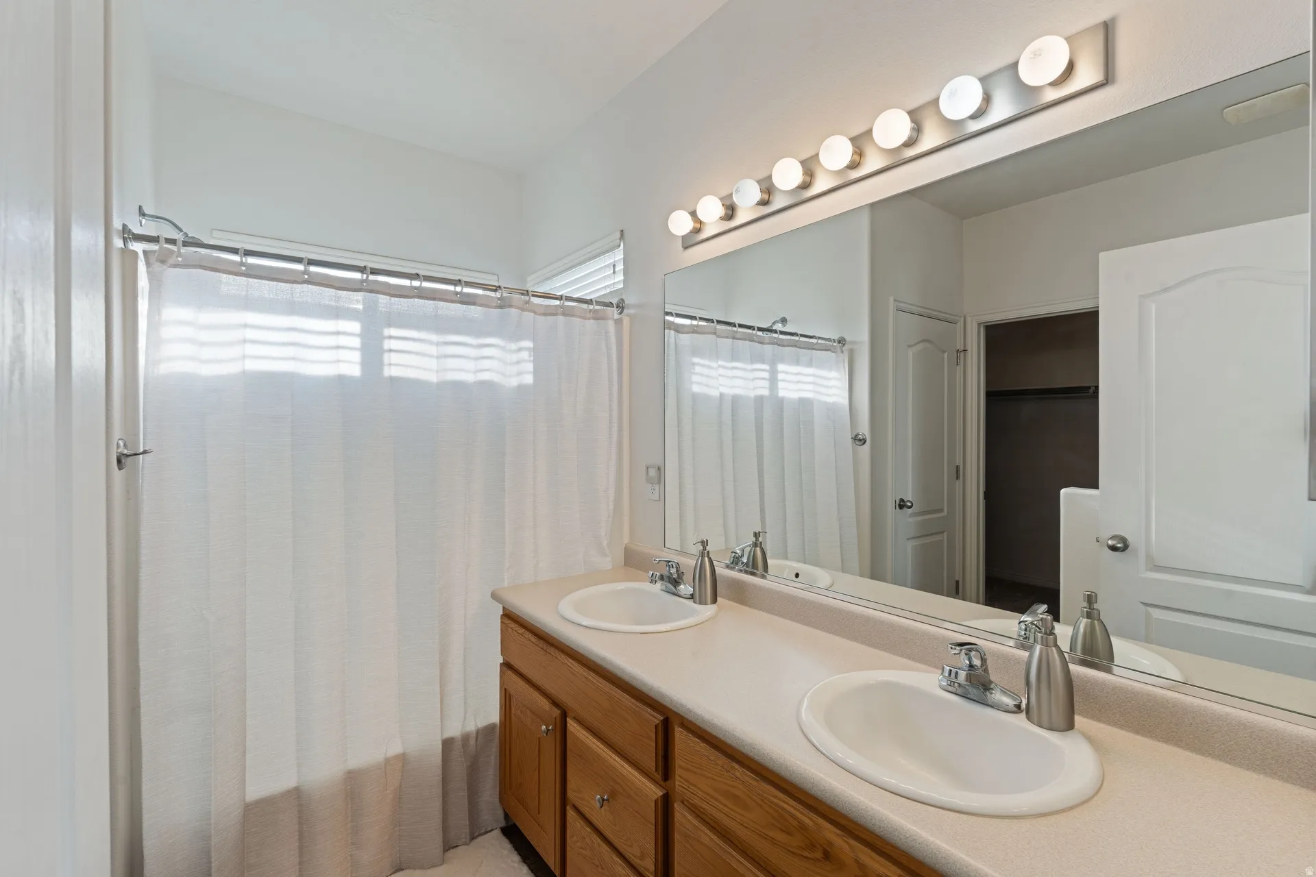 Double vanity with undermount sinks, laminate countertop, and wood-finish cabinetry