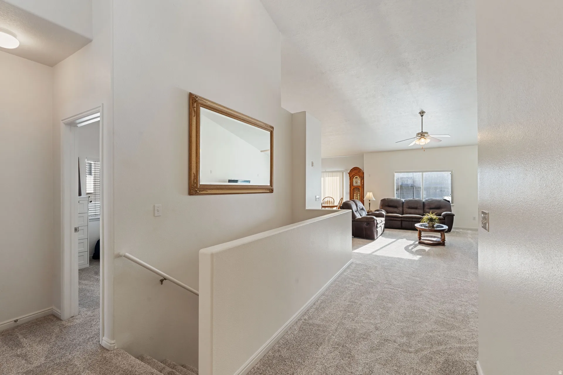 Upper-level landing featuring a white painted handrail and neutral carpet