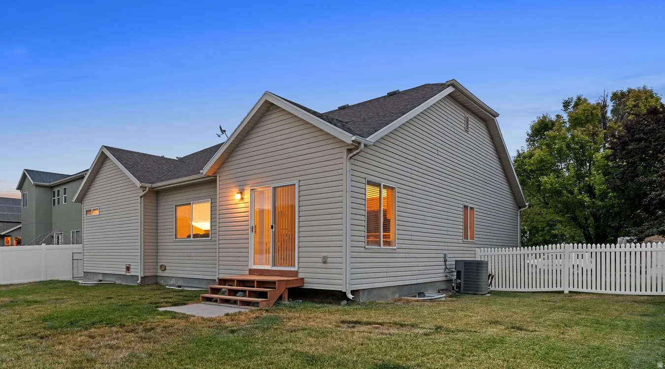Rear exterior with light-colored siding, a wooden deck, and a sliding glass door