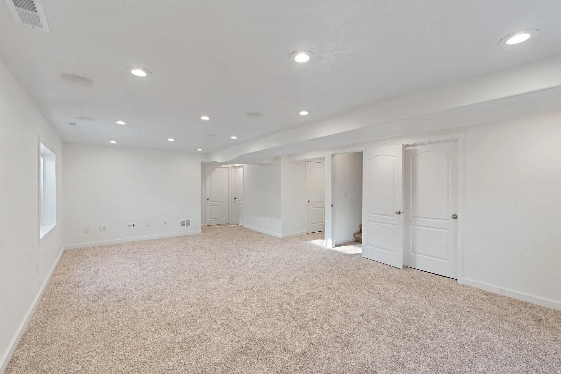 Spacious room featuring neutral carpet flooring, recessed lighting, and crisp white walls