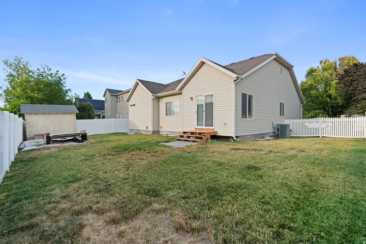 Expansive backyard featuring a manicured lawn, a white vinyl privacy fence, and a white picket fence segment