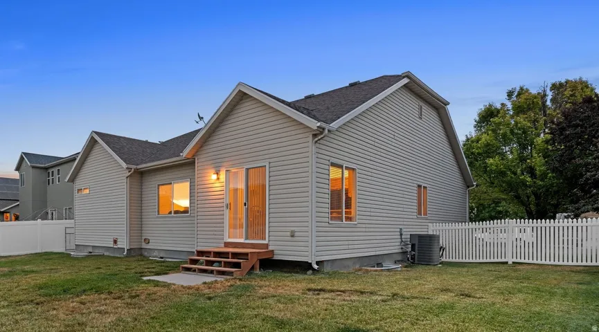 Rear exterior with light-colored siding, a wooden deck, and a sliding glass door