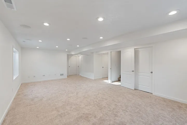 Spacious room featuring neutral carpet flooring, recessed lighting, and crisp white walls