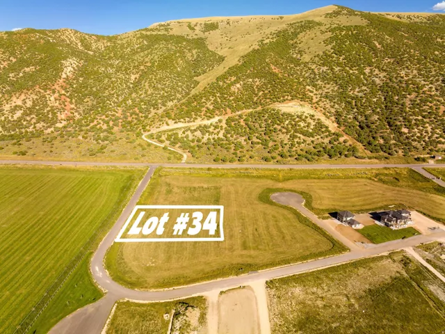 Expansive undeveloped lot with surrounding paved roads, green fields, and distant mountain terrain