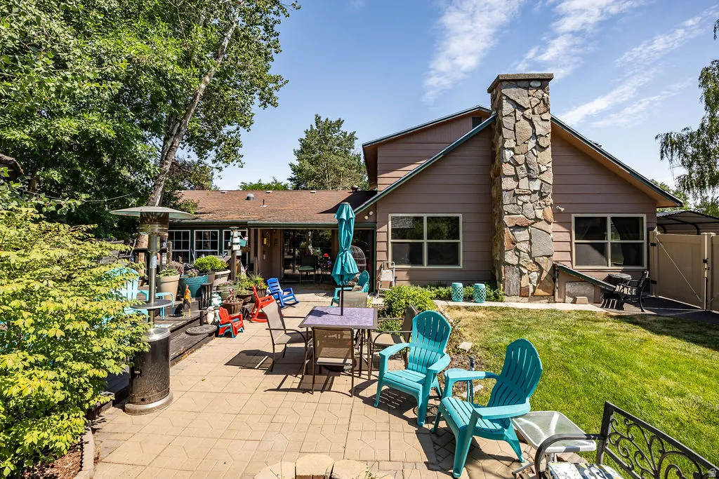 Expansive patio featuring paver stones, a stone-clad chimney, and a sloped lawn