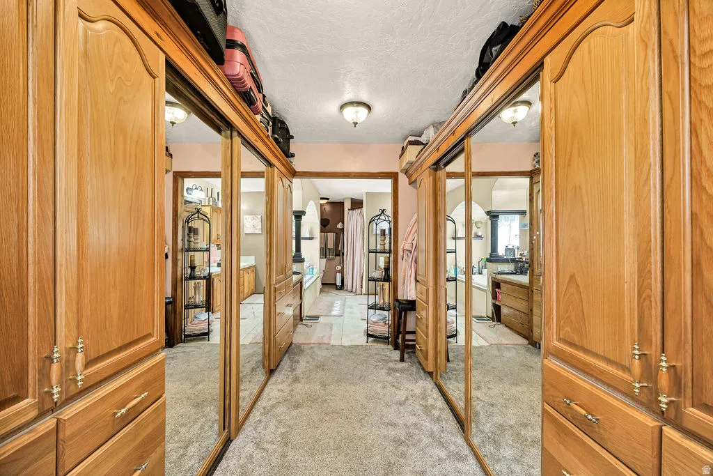Hallway featuring extensive built-in cabinetry with wood-finish doors, mirrored sliding doors, and brass-tone hardware