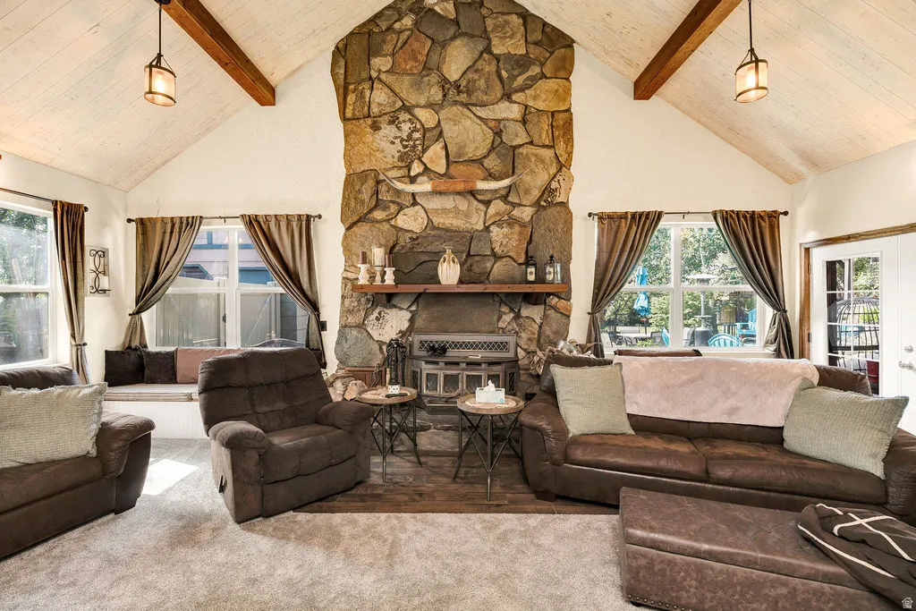 Living area featuring a floor-to-ceiling stone fireplace, vaulted ceiling with exposed wood beams, and a built-in window seat