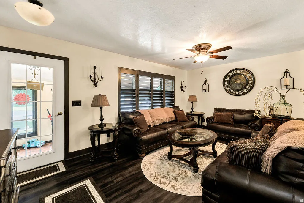 Spacious living area featuring dark wood-finish flooring and a ceiling fan