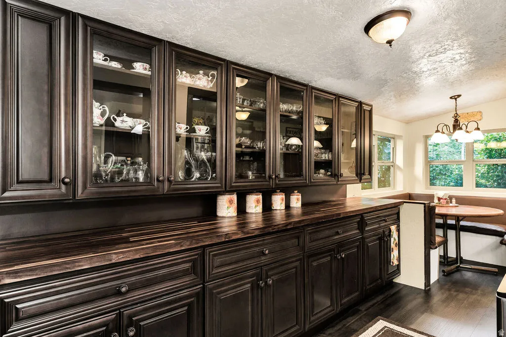 Dark wood cabinetry with glass-front upper cabinets, complementing wood-finish countertops, and dark wood-finish flooring