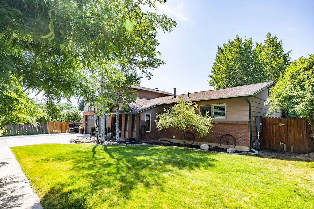 Split-level residence featuring a brick and siding exterior, front lawn, mature trees, and a concrete driveway