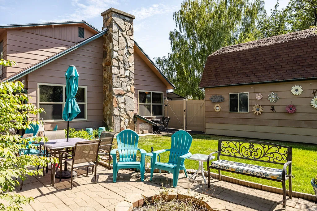 Paver patio with a stone fire pit, featuring a stone-clad chimney on the main residence
