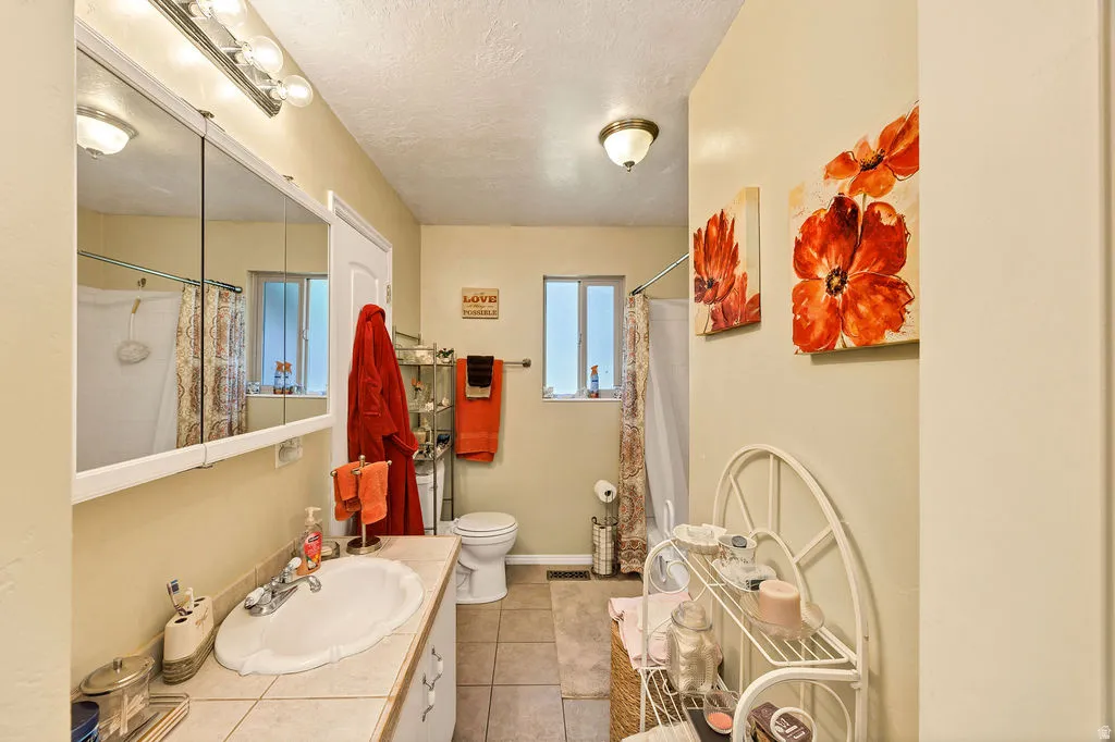 Bathroom featuring a white vanity with an integrated sink, a large mirrored medicine cabinet with overhead lighting, and tile flooring