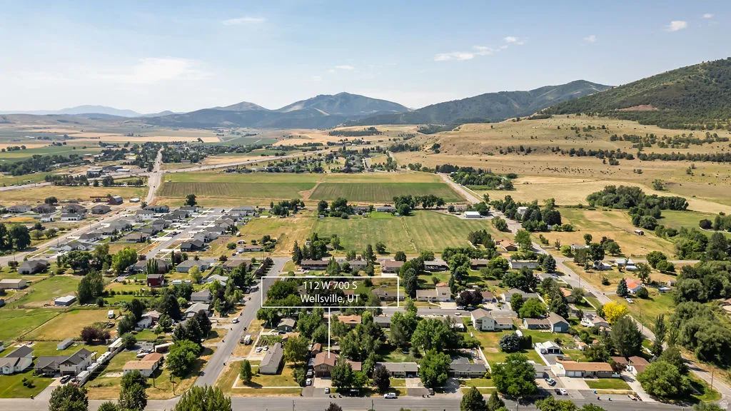 Aerial view of a residential neighborhood with surrounding agricultural fields and distant mountains