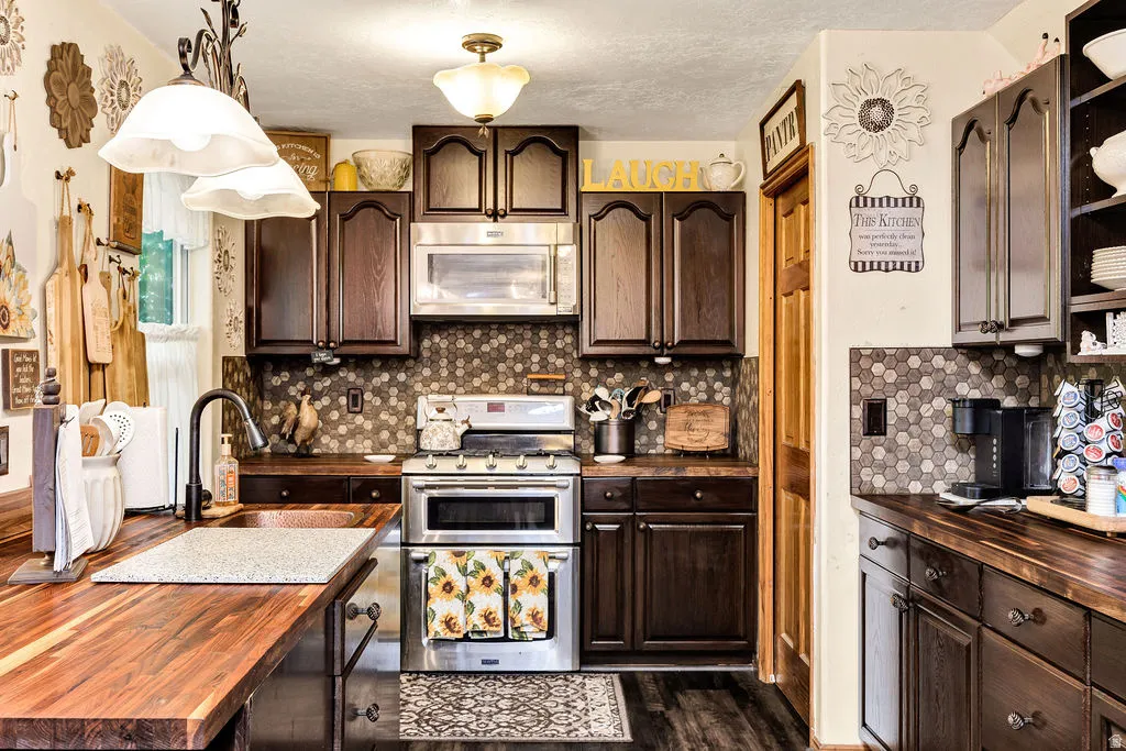 Kitchen featuring wood-finish countertops, dark wood cabinetry, and a mosaic tile backsplash
