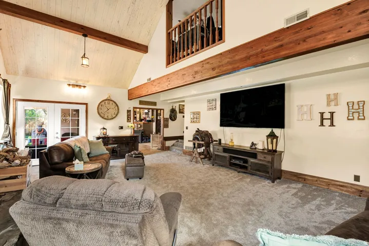 Spacious living area featuring a vaulted ceiling with exposed wood beams and paneling