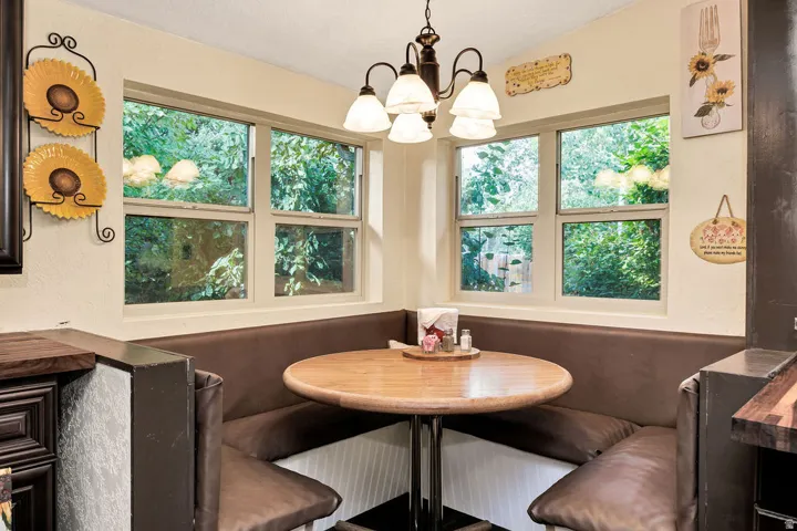 Built-in corner bench seating with a round wood-finish table, illuminated by a multi-bulb chandelier