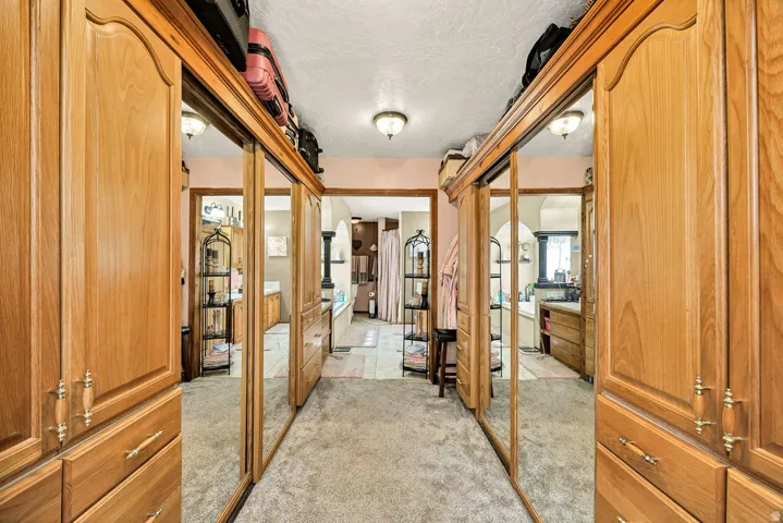 Hallway featuring extensive built-in cabinetry with wood-finish doors, mirrored sliding doors, and brass-tone hardware
