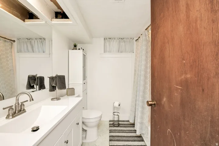 Bathroom featuring a white vanity with an integrated sink, brushed nickel faucet, and under-sink cabinetry