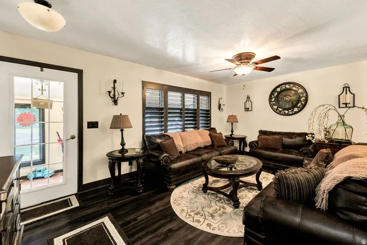 Spacious living area featuring dark wood-finish flooring and a ceiling fan