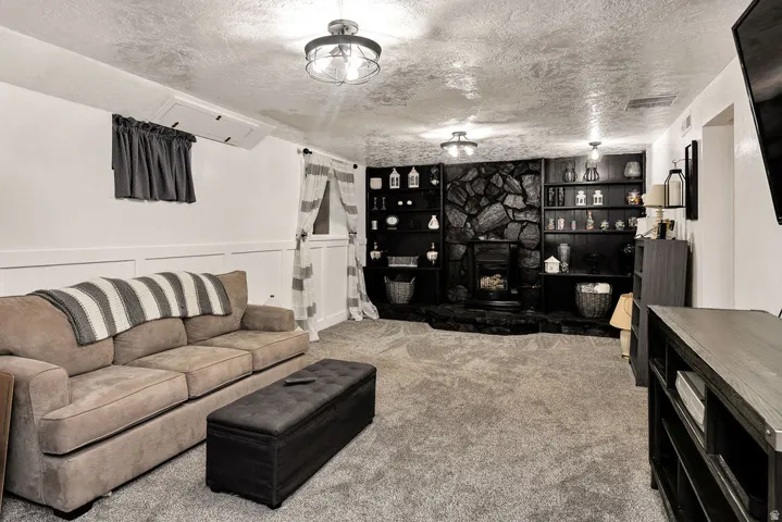Spacious room featuring a stone-clad fireplace with a hearth, integrated shelving, and recessed lighting