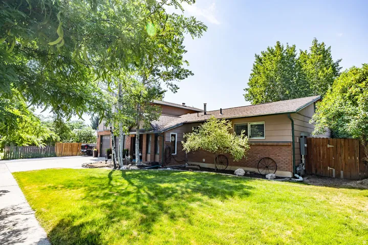 Split-level residence featuring a brick and siding exterior, front lawn, mature trees, and a concrete driveway
