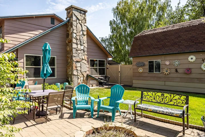 Paver patio with a stone fire pit, featuring a stone-clad chimney on the main residence