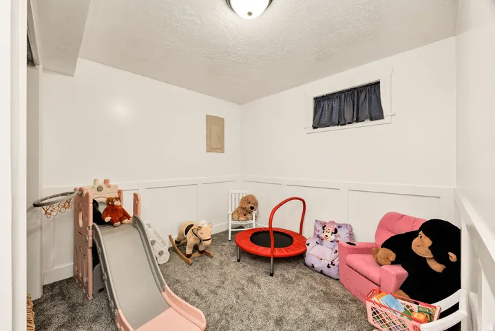 Carpeted room with white paneled wainscoting, white walls, and a small window with a dark curtain