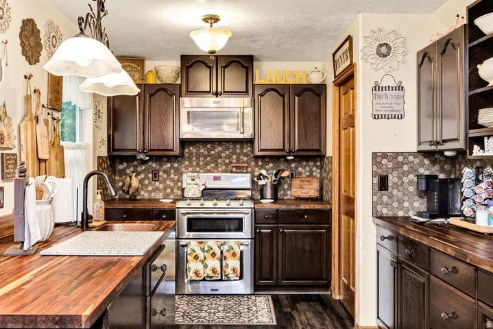 Kitchen featuring wood-finish countertops, dark wood cabinetry, and a mosaic tile backsplash