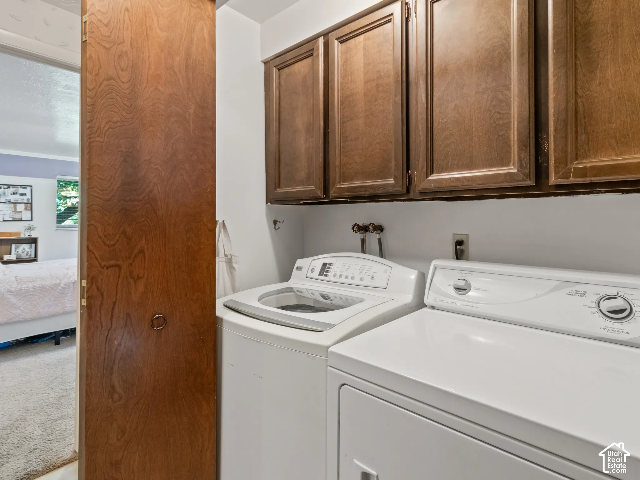 Laundry area featuring overhead wood cabinetry, a top-load washing machine, and a front-load dryer