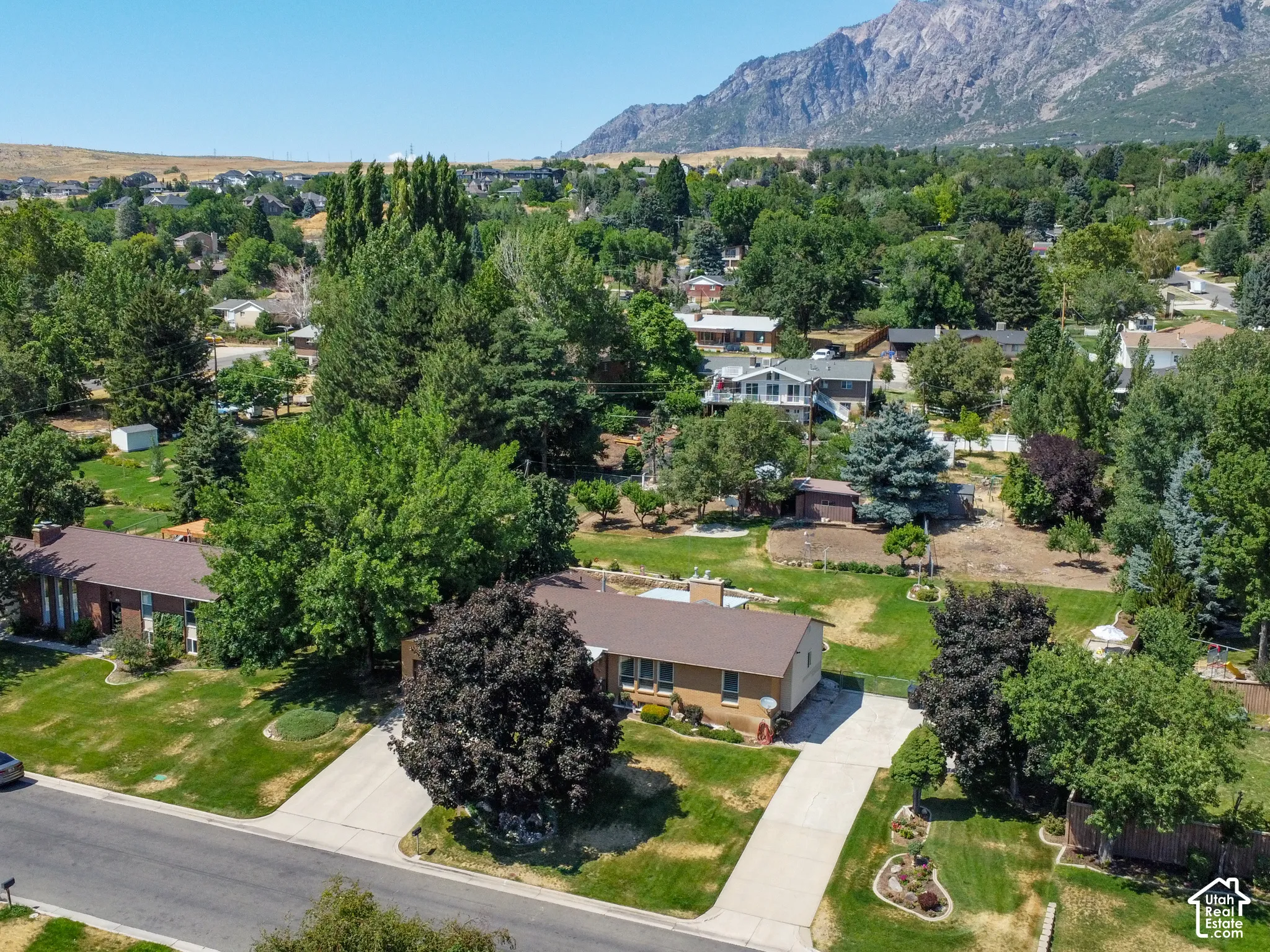Expansive lot featuring a single-story residence with a brown shingle roof and light brown brick exterior