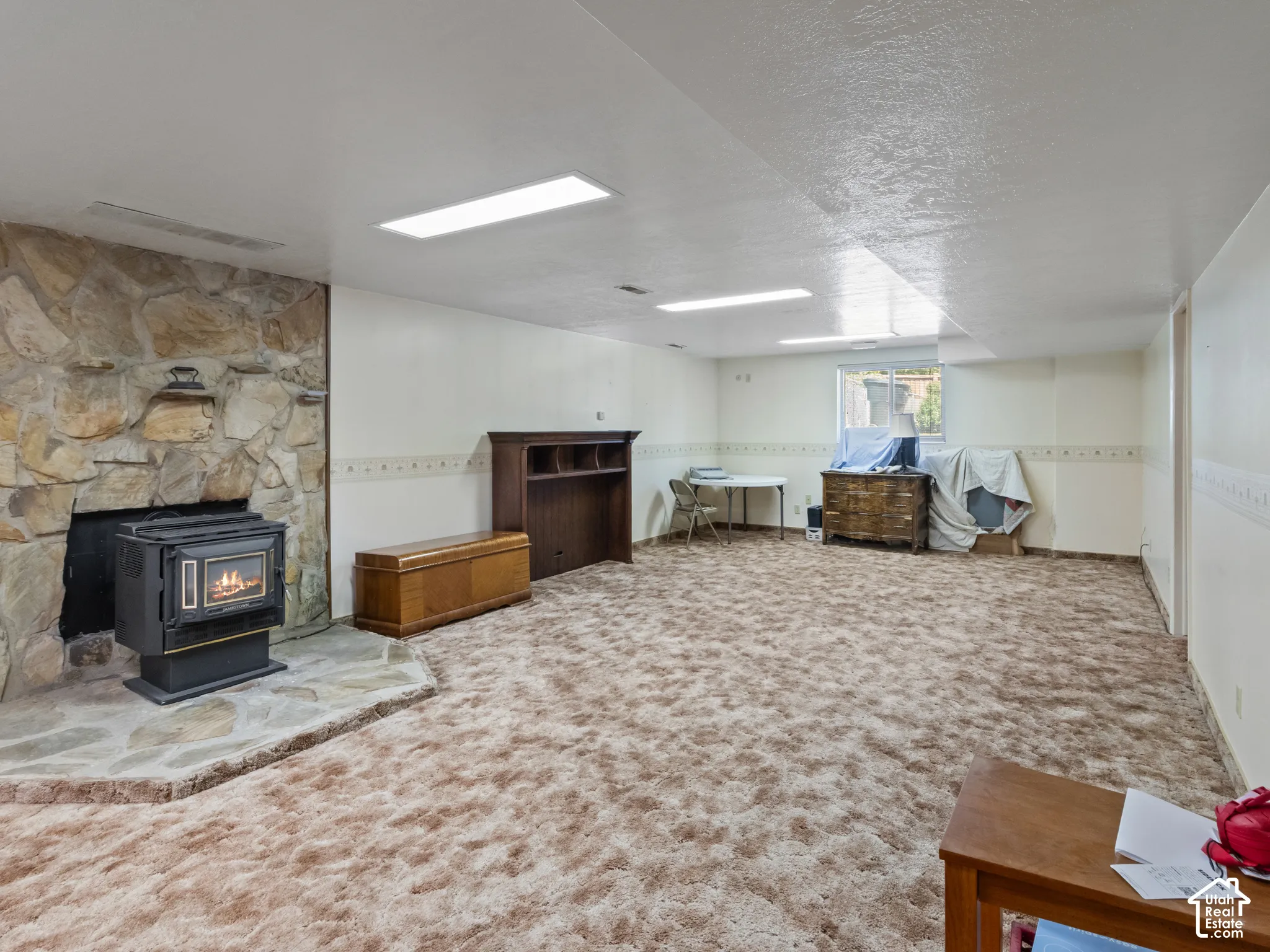 Spacious finished room featuring a stone-clad fireplace with an insert, plush carpeting, and recessed lighting