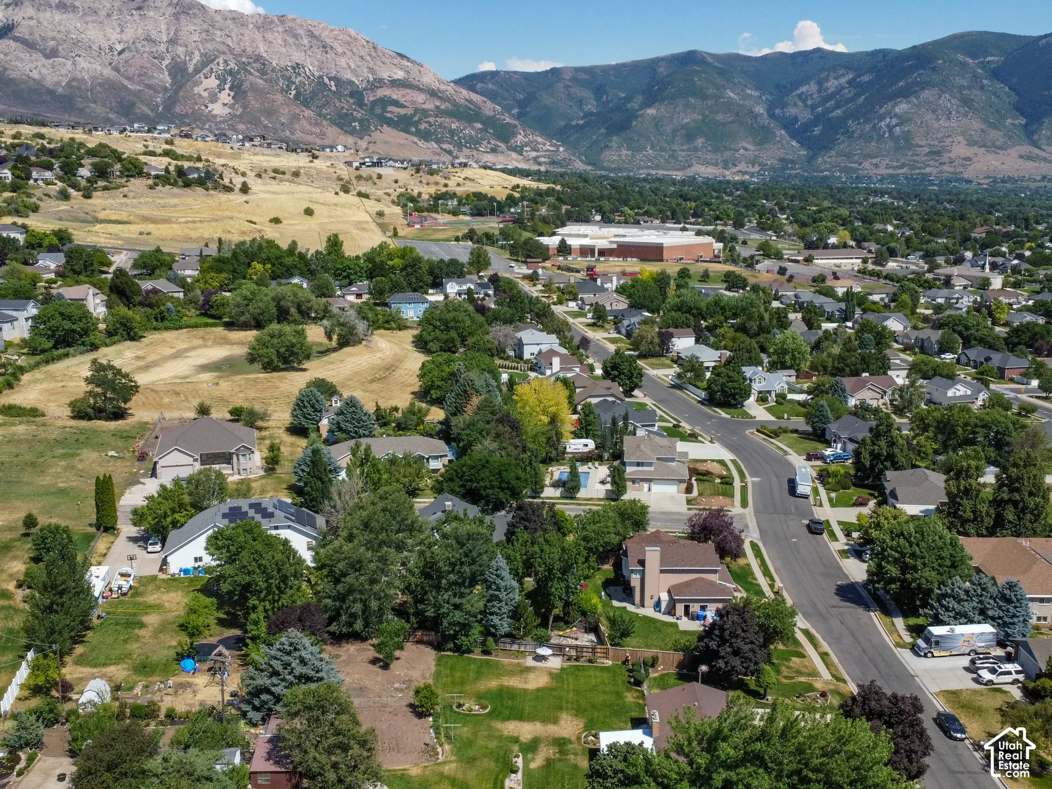 Residential area featuring paved streets, mature trees, and a distant mountain range