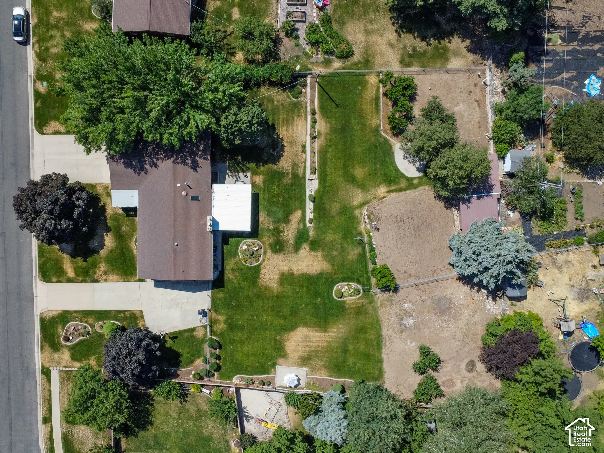 Expansive property featuring a brown shingle roof, established landscaping, a concrete driveway, and substantial yard space