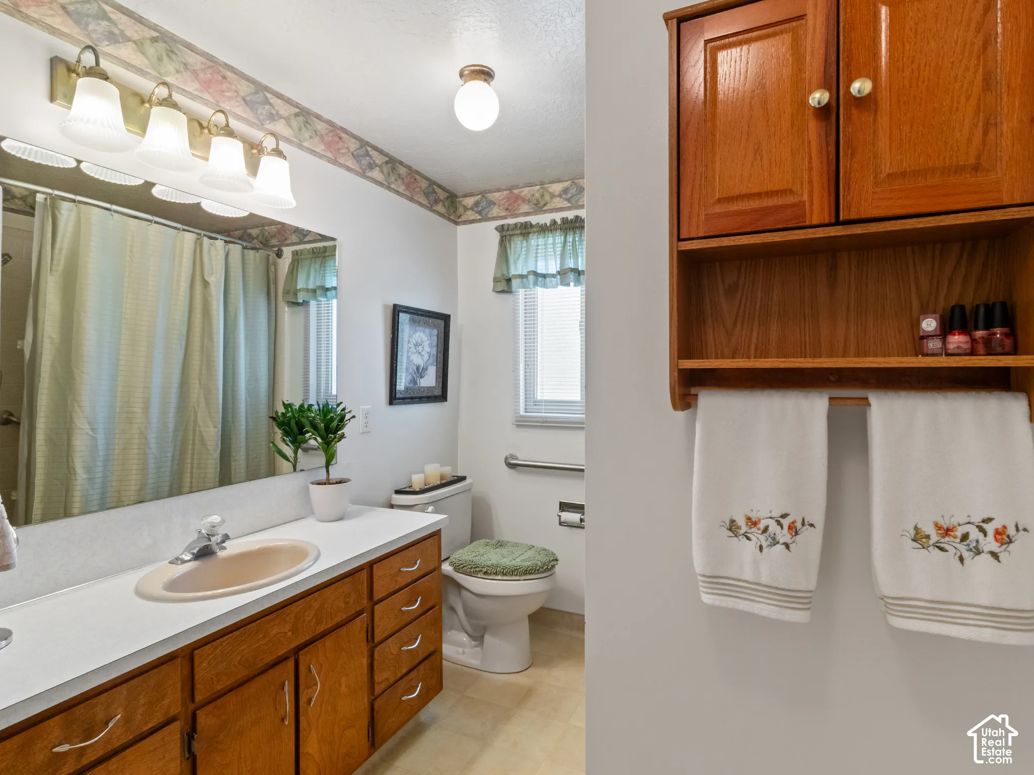 Bathroom featuring a vanity with an integrated sink and wood-finish cabinetry, a large mirror, and a wall-mounted light fixture