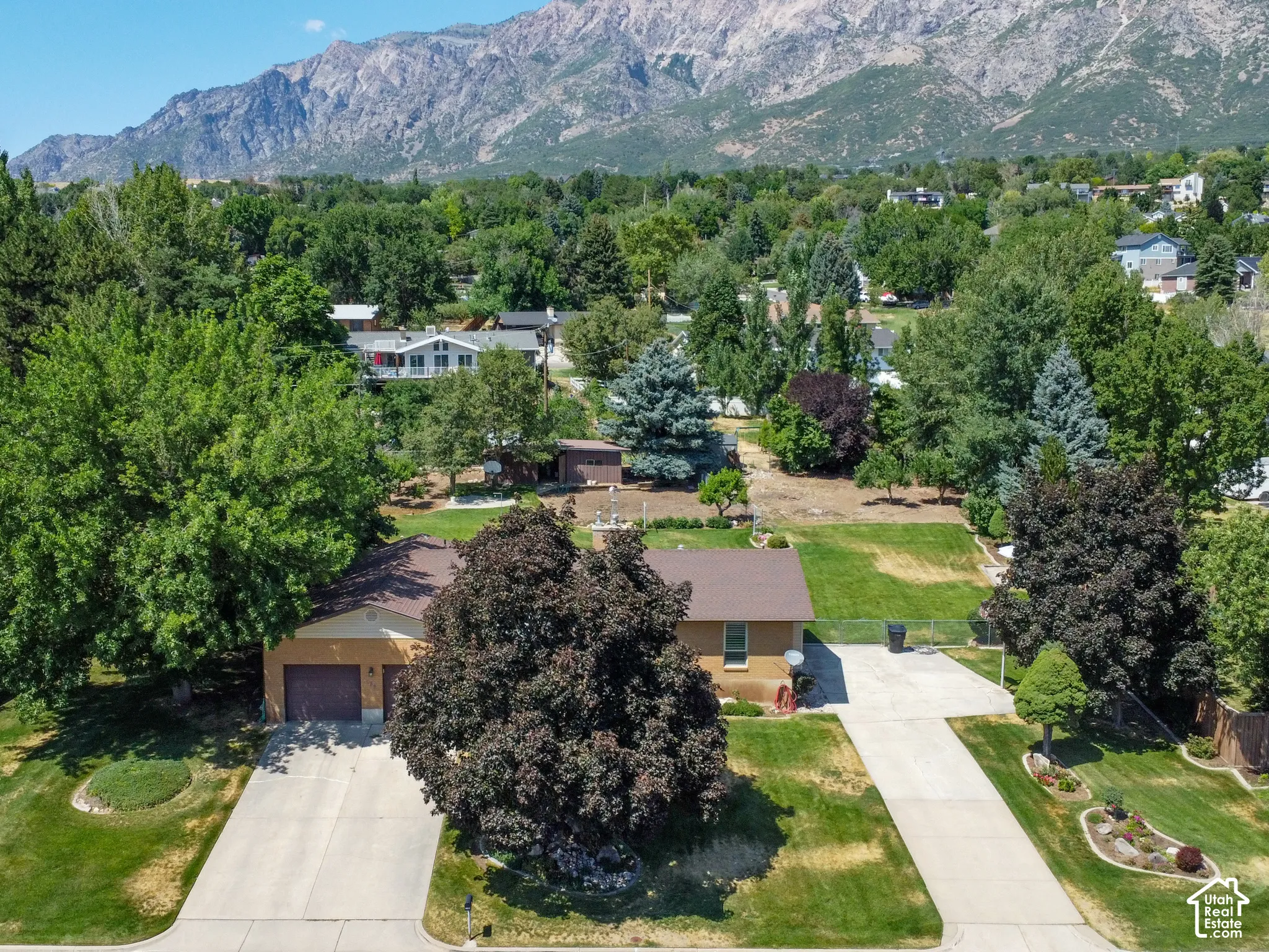 Ranch-style residence featuring a two-car garage, concrete driveway, and mature landscaping