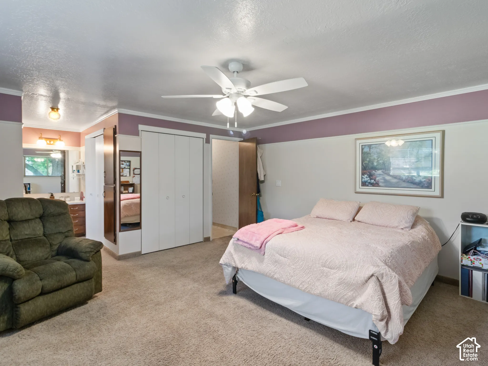 Carpeted room featuring a ceiling fan, base molding, a wall-mounted light fixture, and bifold closet doors