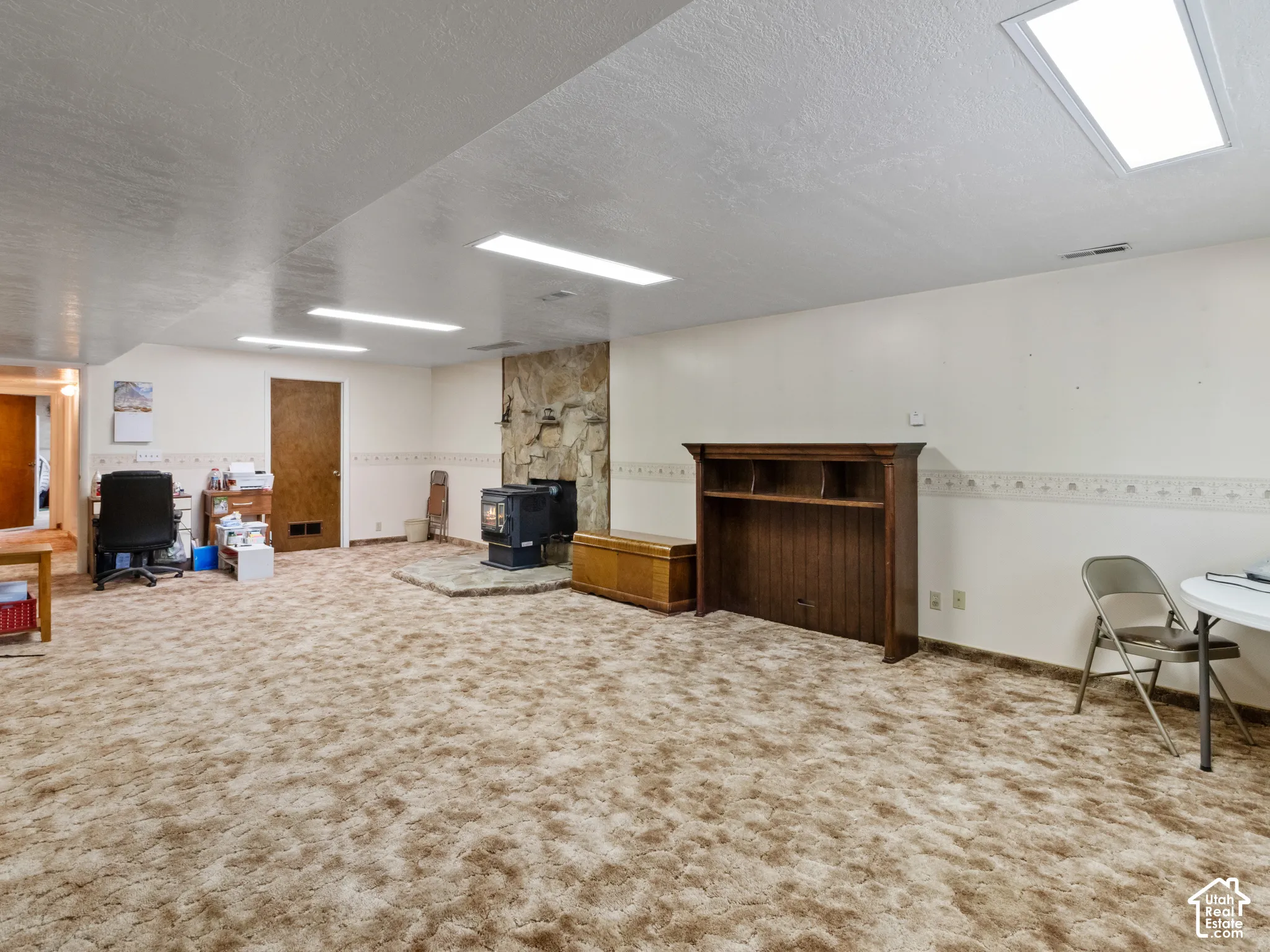 Spacious room featuring a stone-clad fireplace with a hearth, wall-to-wall carpeting, and recessed ceiling lighting
