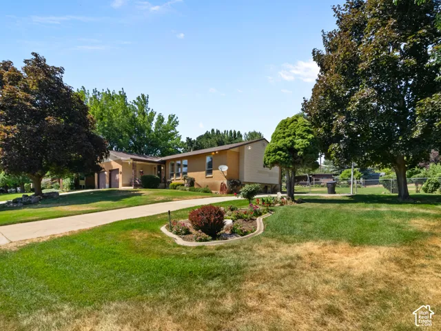 Brick facade residence with a multi-car garage, mature shade trees, and a concrete driveway