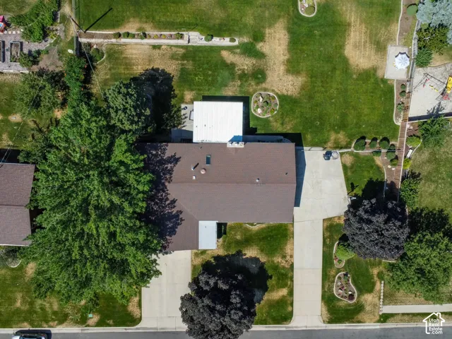 Expansive lot featuring a large residential structure with a brown shingle roof, two distinct concrete driveways, mature trees, and a substantial green lawn area