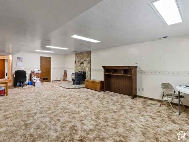 Spacious room featuring a stone-clad fireplace with a hearth, wall-to-wall carpeting, and recessed ceiling lighting
