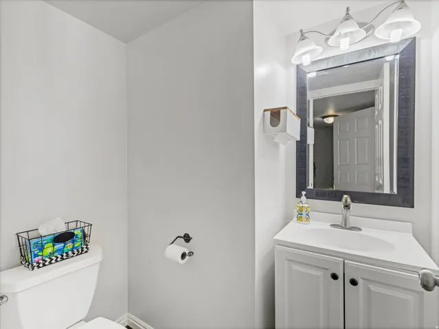 Bathroom featuring a white vanity with integrated sink, chrome faucet, framed mirror, and a three-light fixture